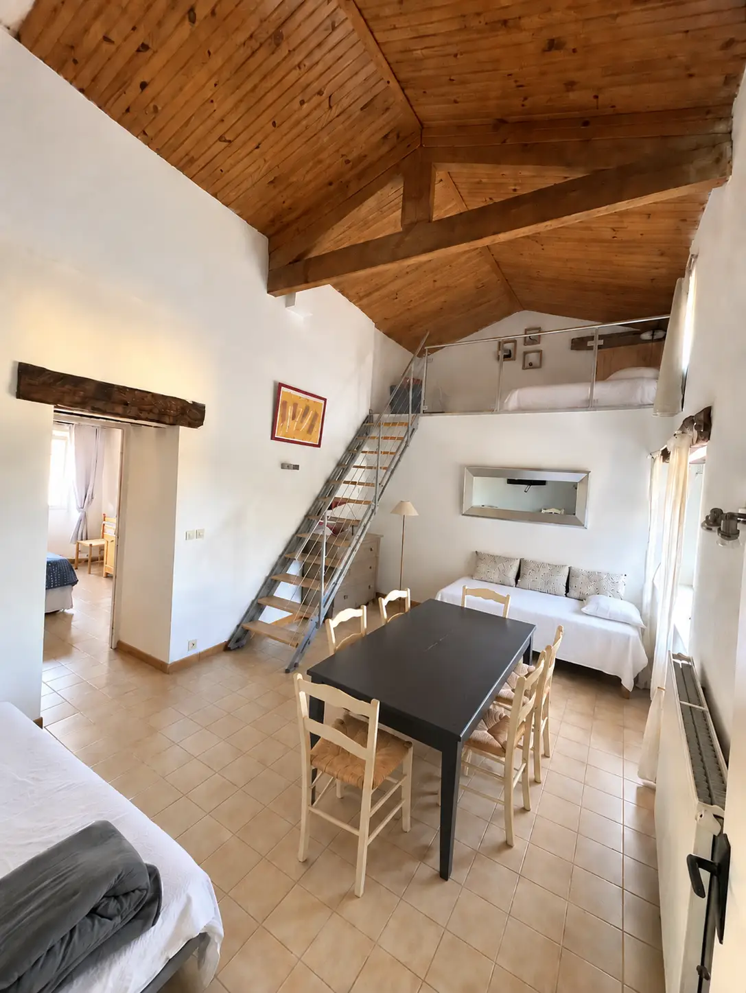Pièce de vie de la Châteaunette, avec table, cuisine et poutres apparentes.