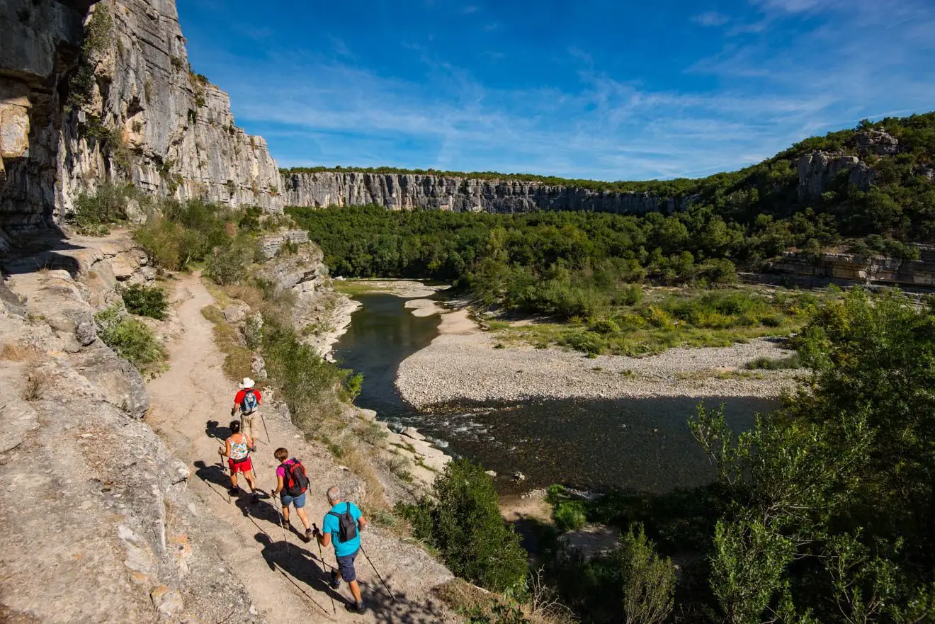 Randonneurs sur un sentier rocheux au-dessus d’une rivière entre les falaises