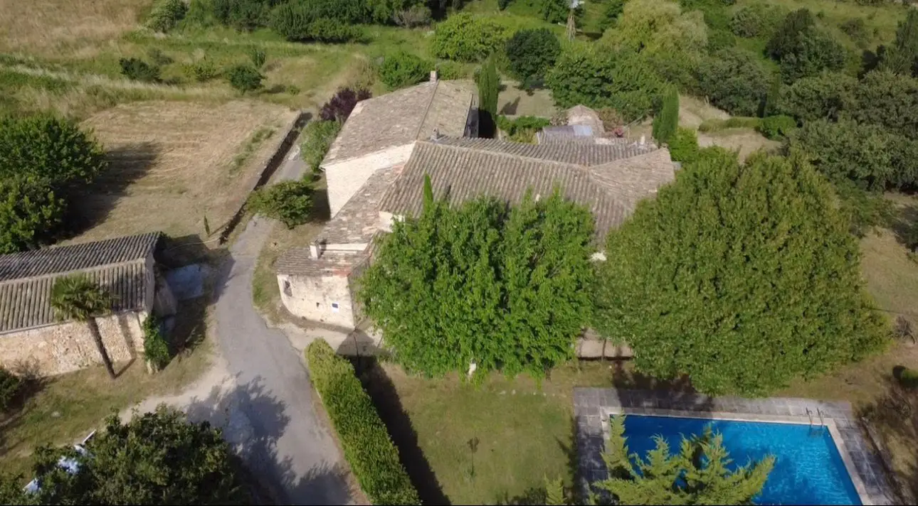 Vue aérienne des bâtiments, des arbres et de la piscine du Mas d'Eylieux à Saint-Montan.
